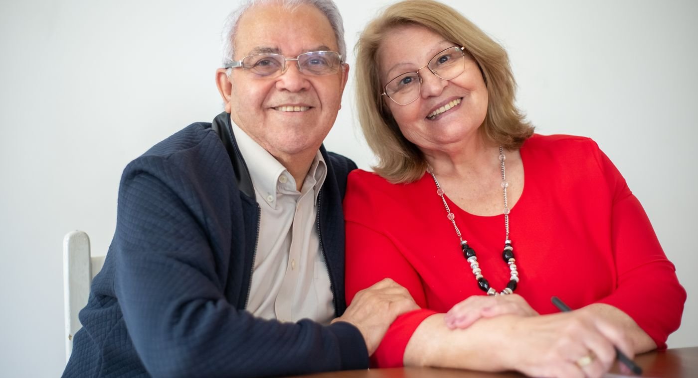 Casal sorrindo à mesa ao assinar um documento